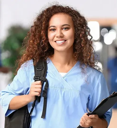 Mulher de mochila sorrindo segundando uma prancheta